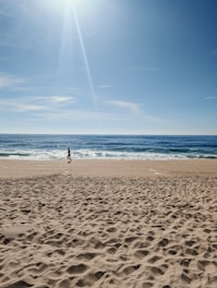 Athlete sprinting intensely on a sandy beach under a bright sun.