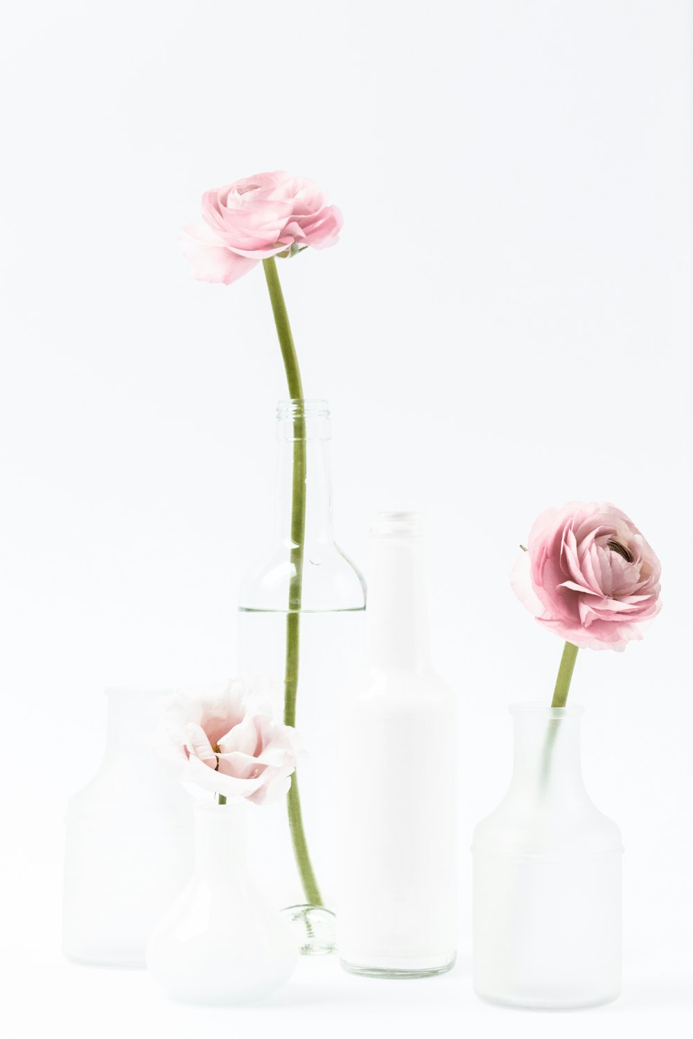 three white vases with pink flowers in them