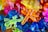 A vibrant assortment of colorful, translucent plastic animal toys including scorpions, lizards, and insects. The toys overlap and are lit with bright lighting, enhancing the vivid colors and glossy texture.