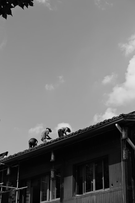 Wide shot of a roof mid-repair showing workers replacing damaged tiles