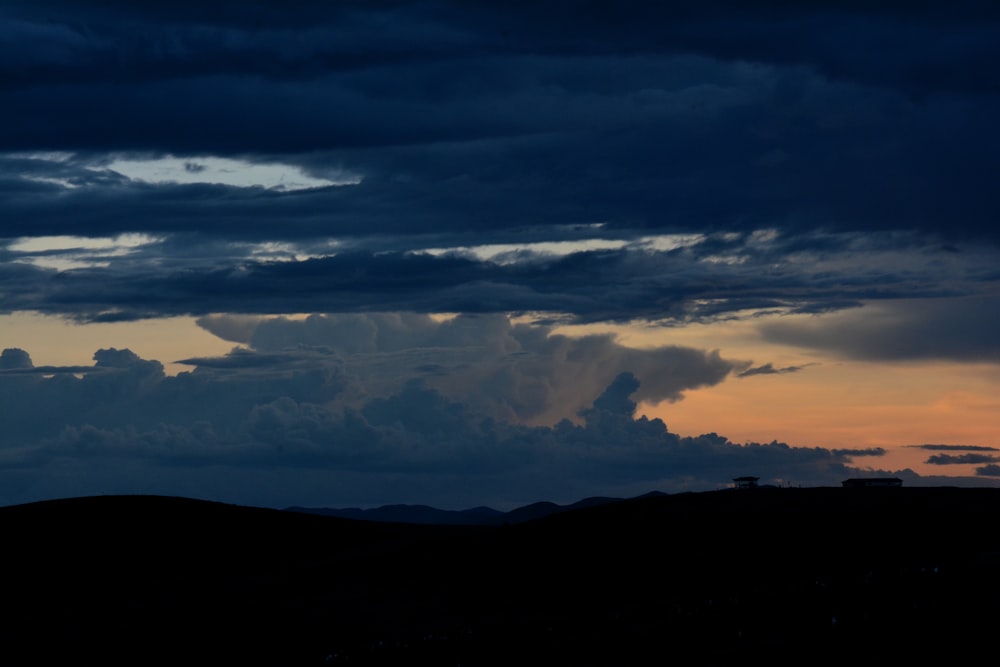 a dark sky with clouds and a plane in the foreground