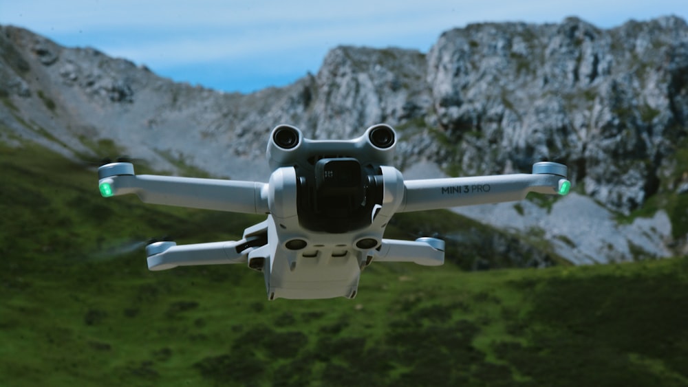 a white and black remote control flying over a mountain