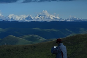 User holding a tablet outdoors with a scenic mountain background