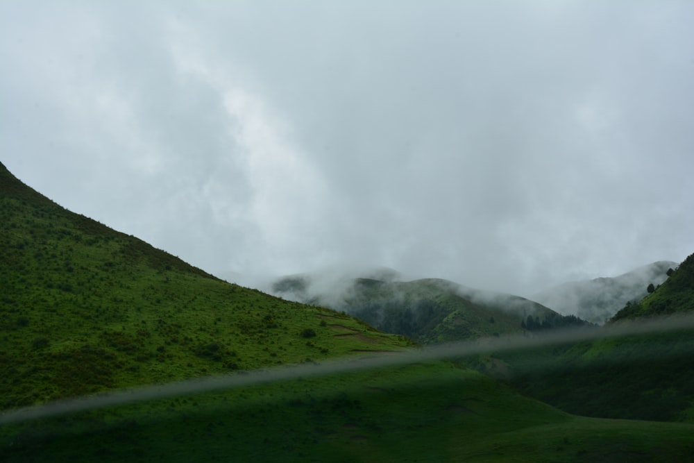 Ein grasbewachsener Hügel mit ein paar Wolken am Himmel