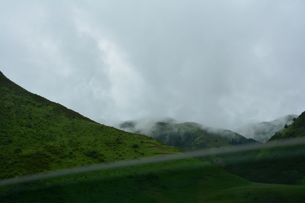 a grassy hill with a few clouds in the sky