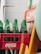 A collection of green Sprite bottles is arranged in a red Coca-Cola crate. The crate is positioned against a tiled wall, partially obscured by other objects. The bottles are empty, and the setup suggests a storage or recycling area.