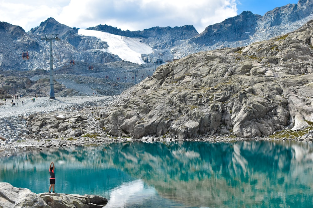 a man standing on top of a rock next to a lake