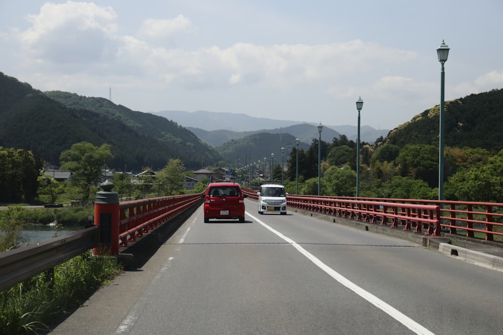 a red bus driving across a bridge over a river