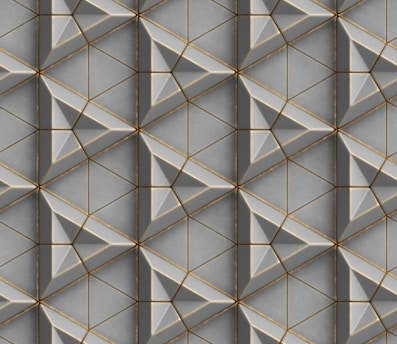 A repeating geometric pattern featuring interlocking triangles and diamond shapes with beveled edges. The design is composed of shades of gray and subtle gold accents, creating a three-dimensional effect.