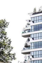 Exterior view of a small, modern building with balconies and greenery around.