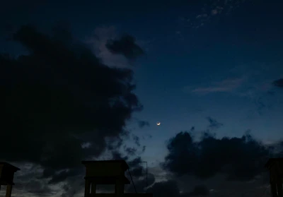 A night sky with a crescent moon shining over a quiet cityscape, symbolizing the calm of the night.