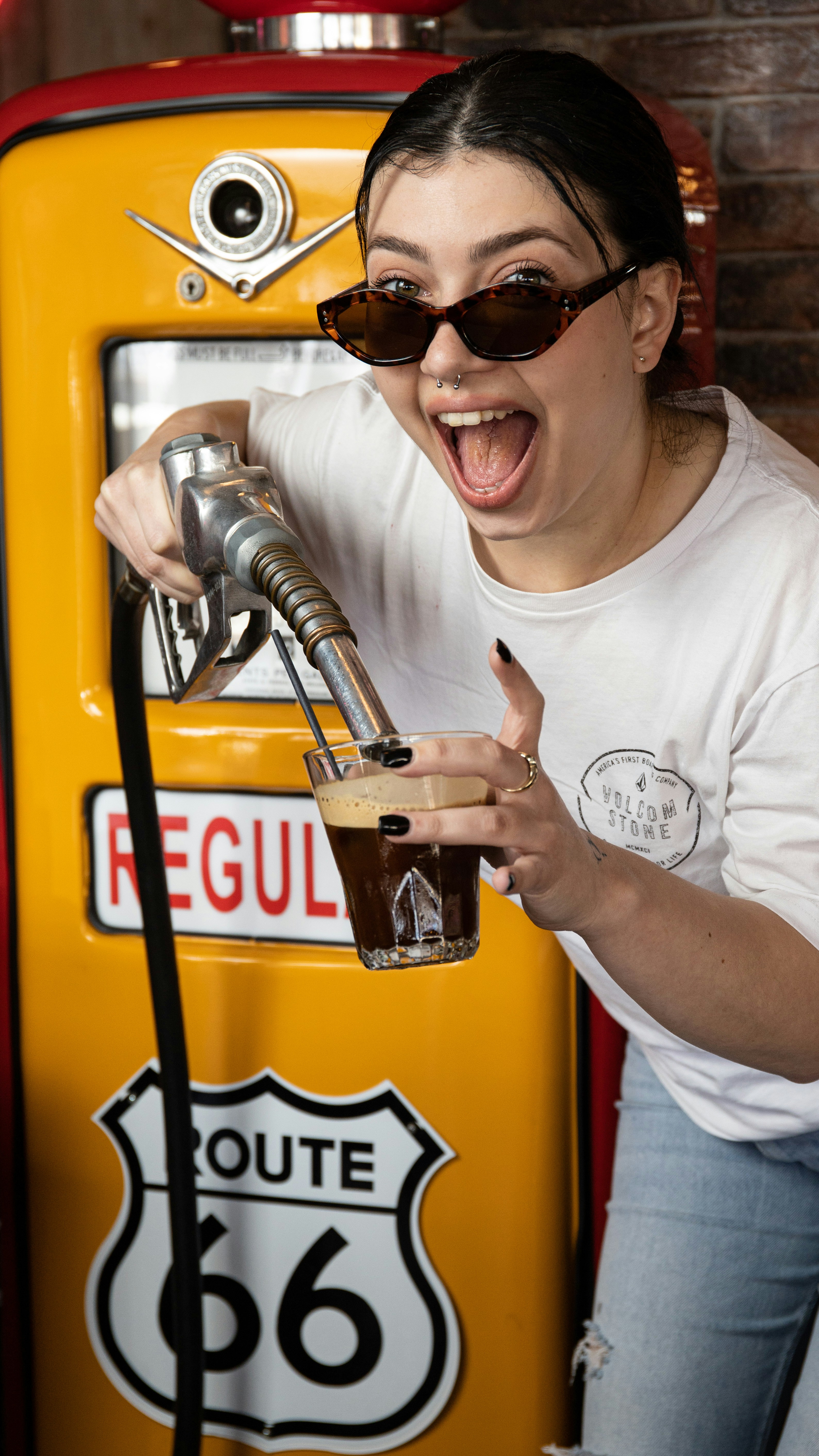 a woman is pumping a glass of beer at a gas pump
