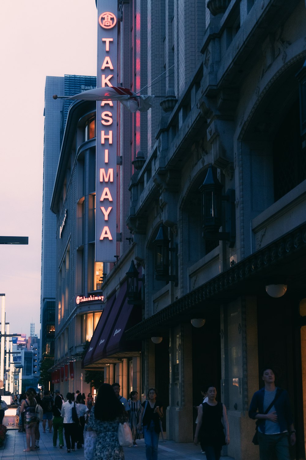 a group of people walking down a street next to tall buildings