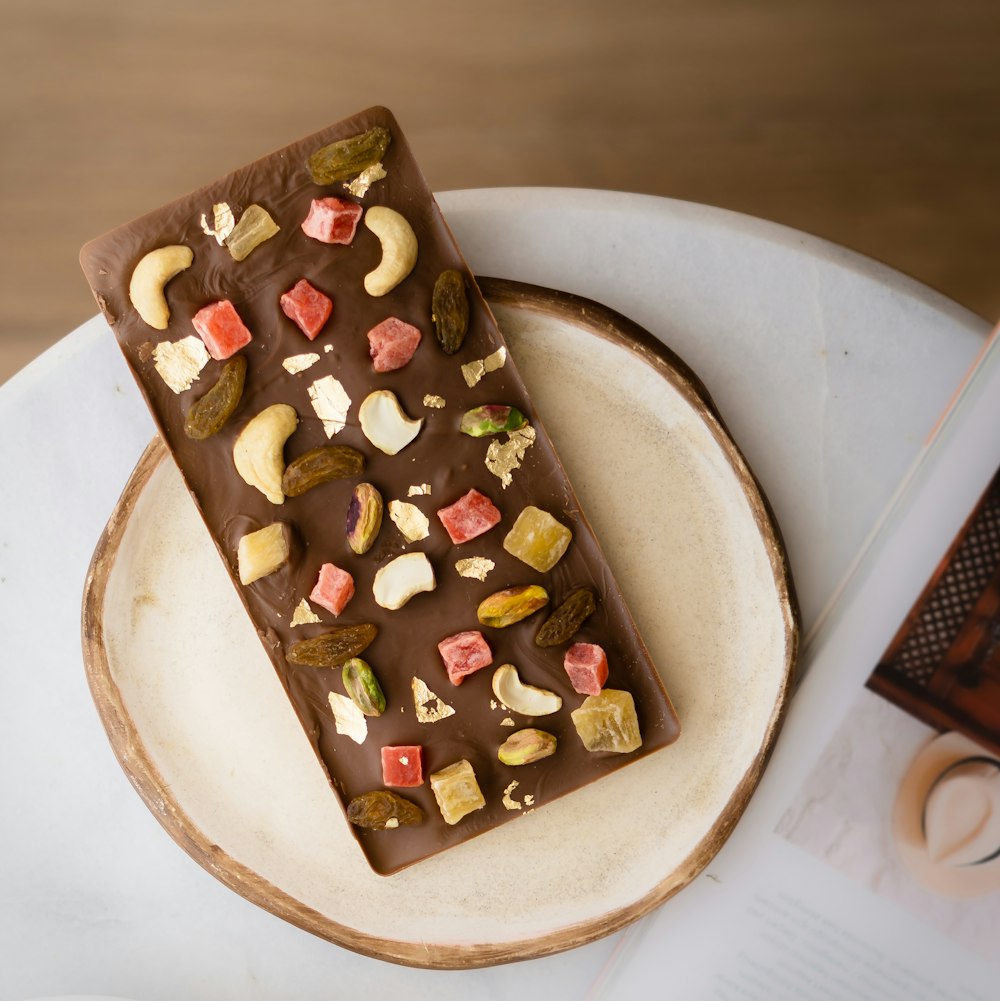a white plate topped with a chocolate bar covered in nuts