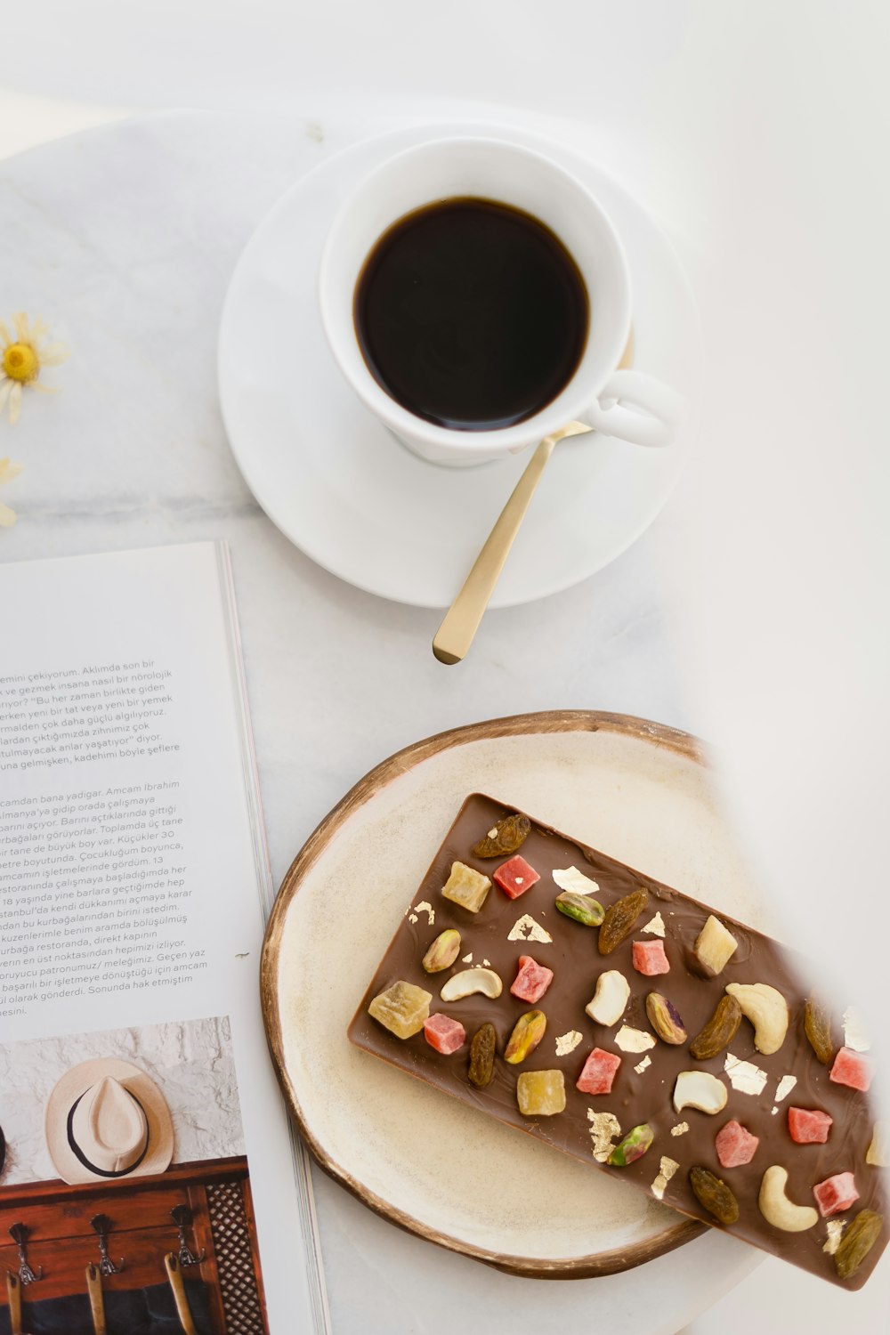 a piece of chocolate on a plate next to a cup of coffee