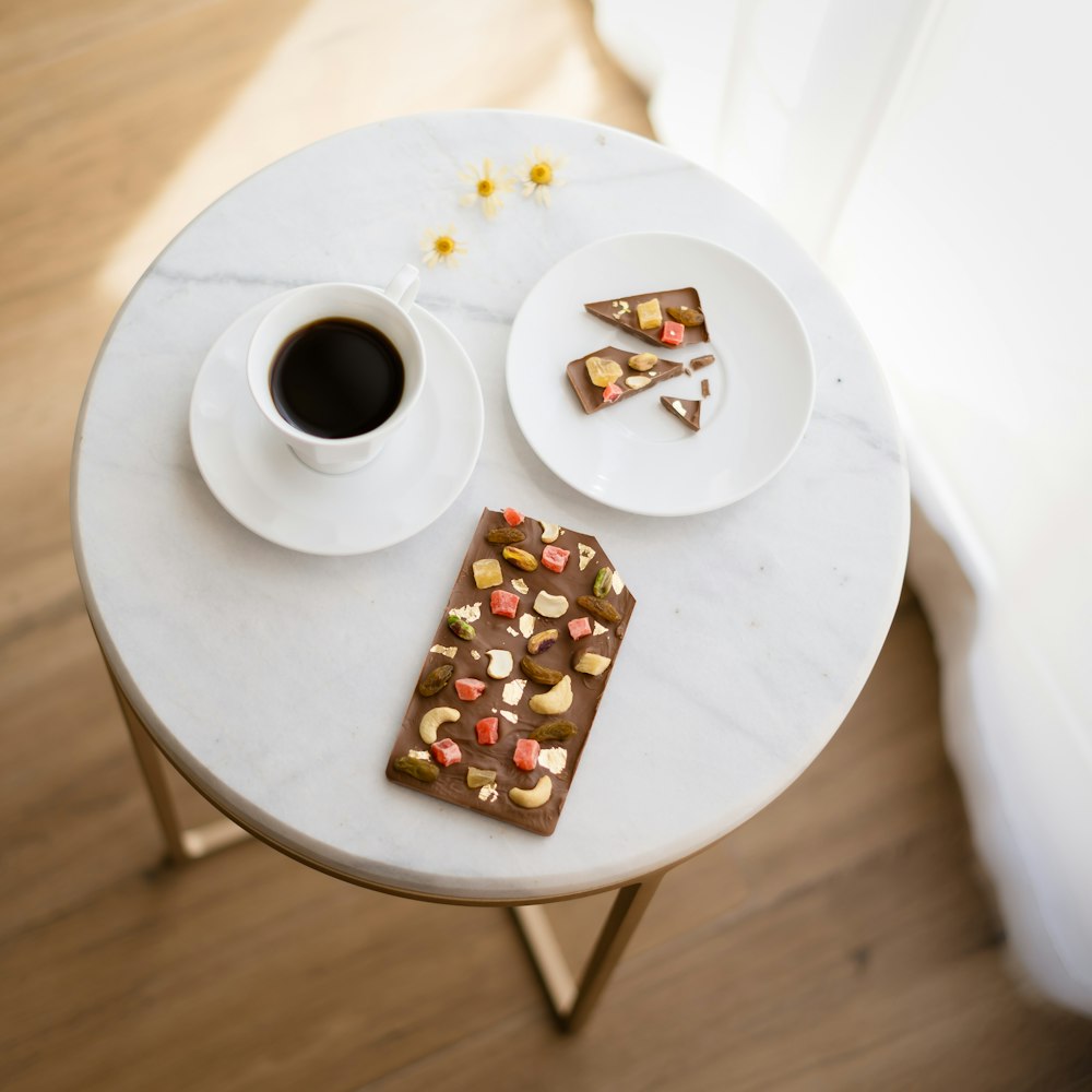 a white table topped with a plate of food and a cup of coffee