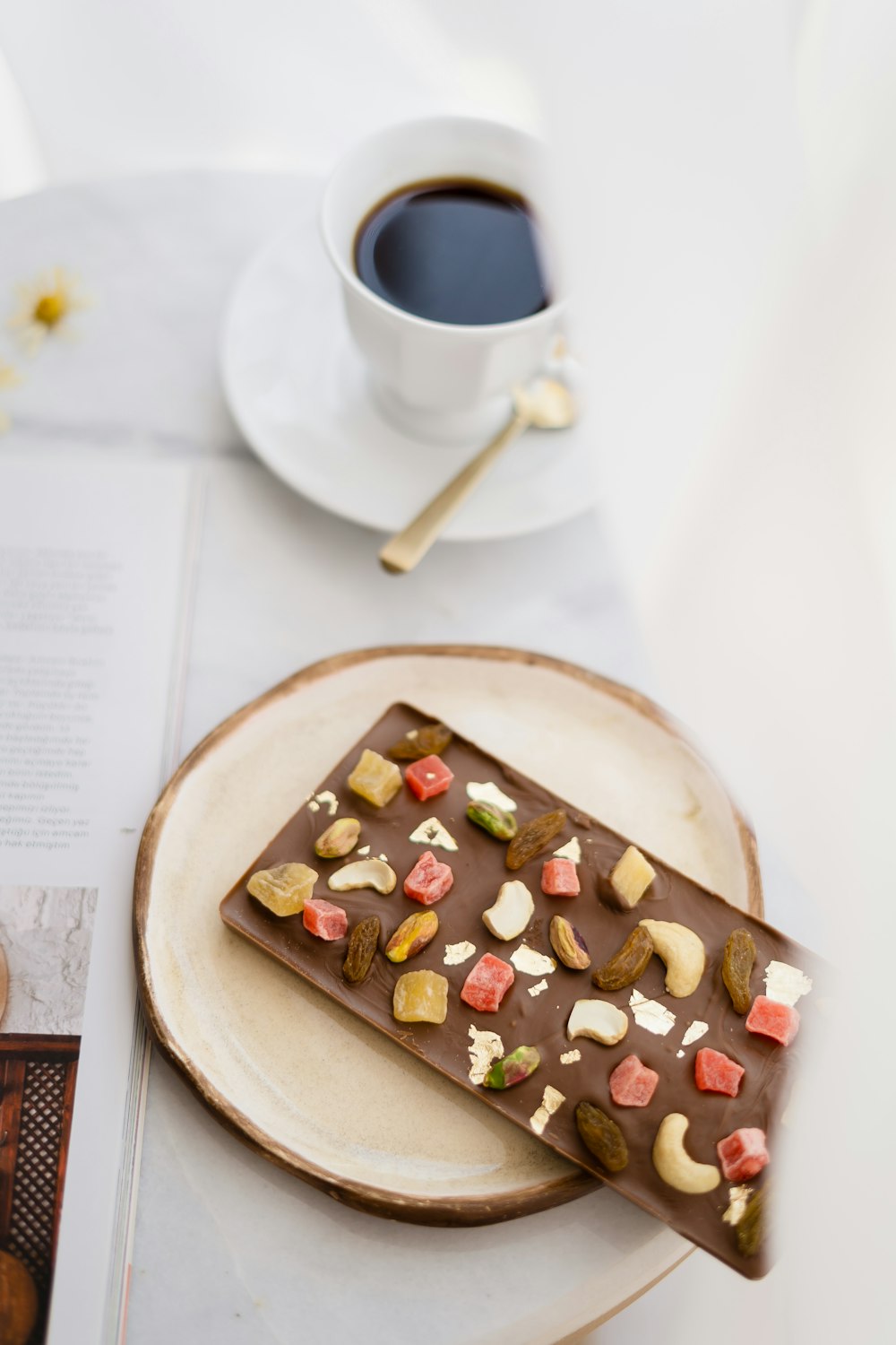 a plate with a piece of chocolate on it next to a cup of coffee