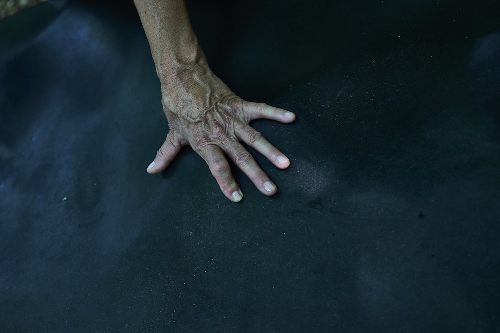 a person's hand resting on a black surface