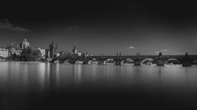 A minimalist photo of an ancient stone bridge silhouetted against a cloudy sky.