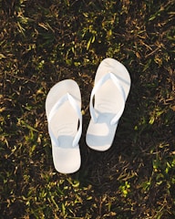 a pair of white slippers sitting on top of a lush green field