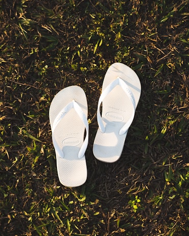 a pair of white slippers sitting on top of a lush green field