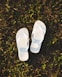 a pair of white slippers sitting on top of a lush green field
