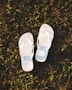 a pair of white slippers sitting on top of a lush green field