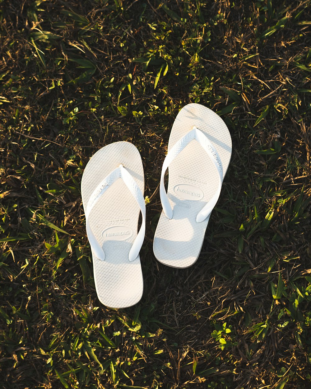 a pair of white slippers sitting on top of a lush green field