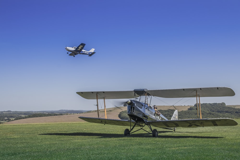 a small plane flying over a lush green field