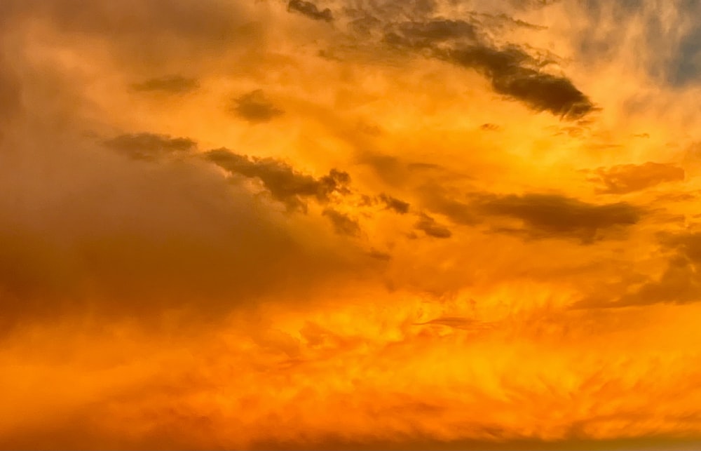 a plane flying through a cloudy sky at sunset