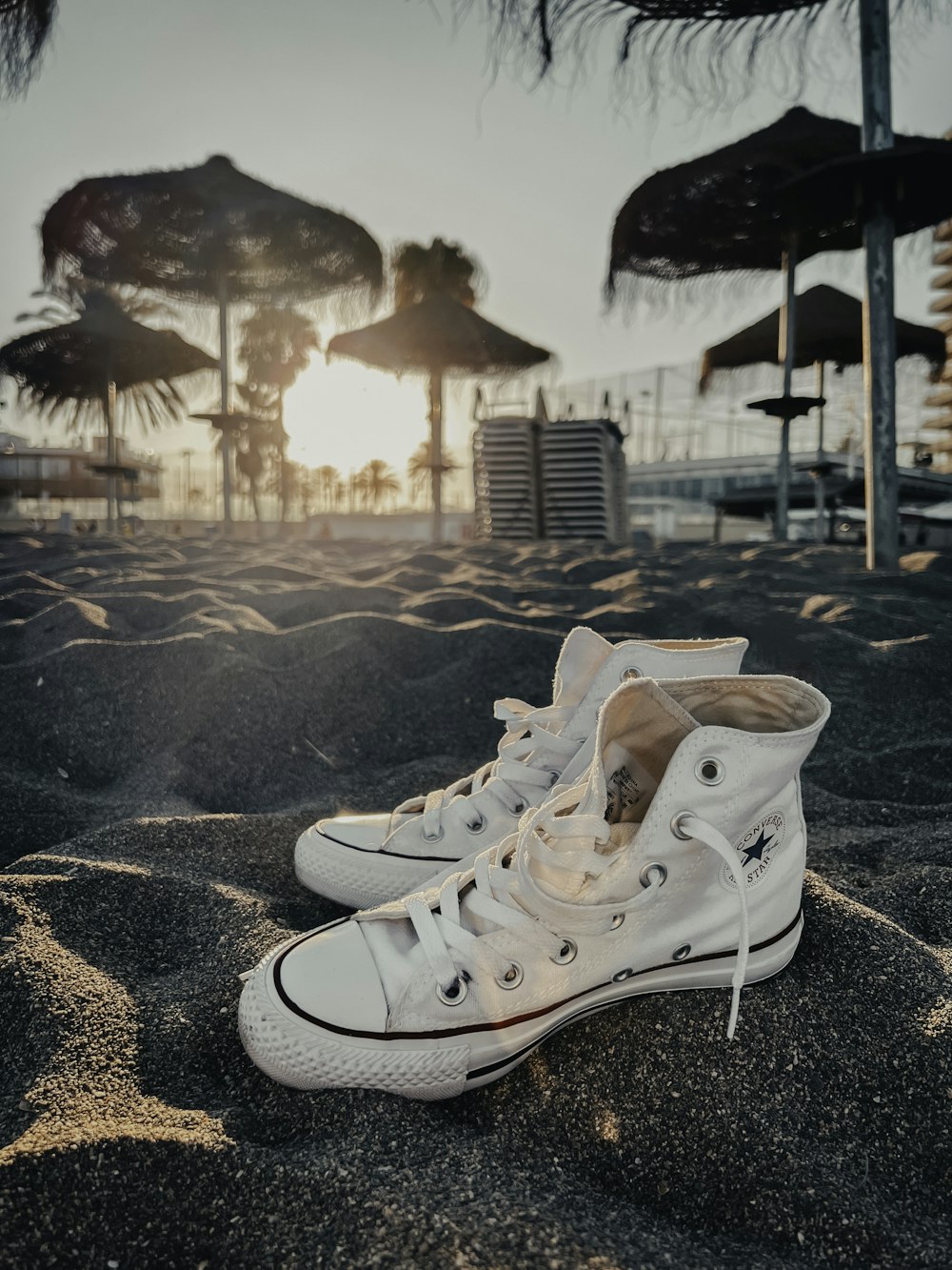 a pair of white sneakers sitting on top of a sandy beach
