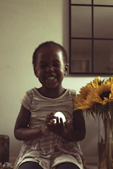 A joyful child looking thoughtfully at a glowing light bulb above their head symbolizing new ideas