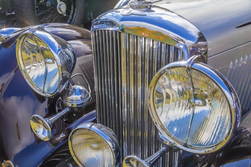 Close-up of a vintage car's polished chrome grille reflecting the city lights.