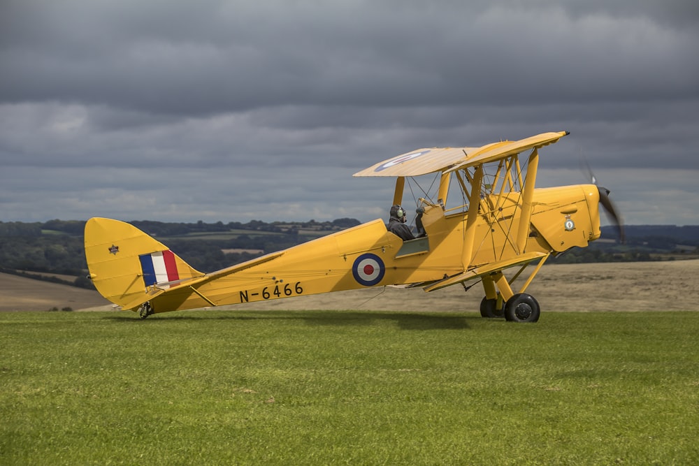 a yellow airplane sitting on top of a lush green field