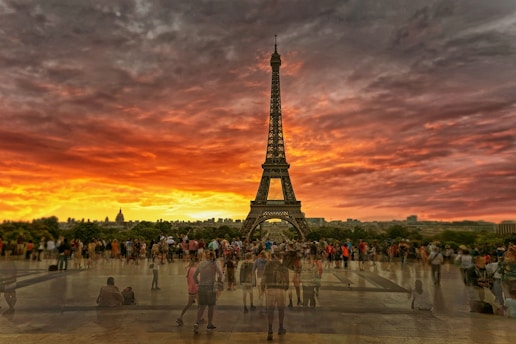 A vibrant sunset view over the Eiffel Tower with travelers admiring the scene.