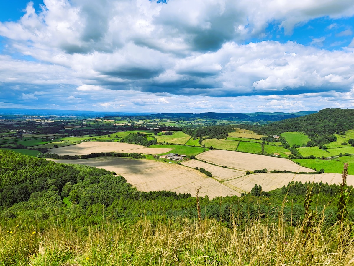 a scenic view of a green countryside under a cloudy sky