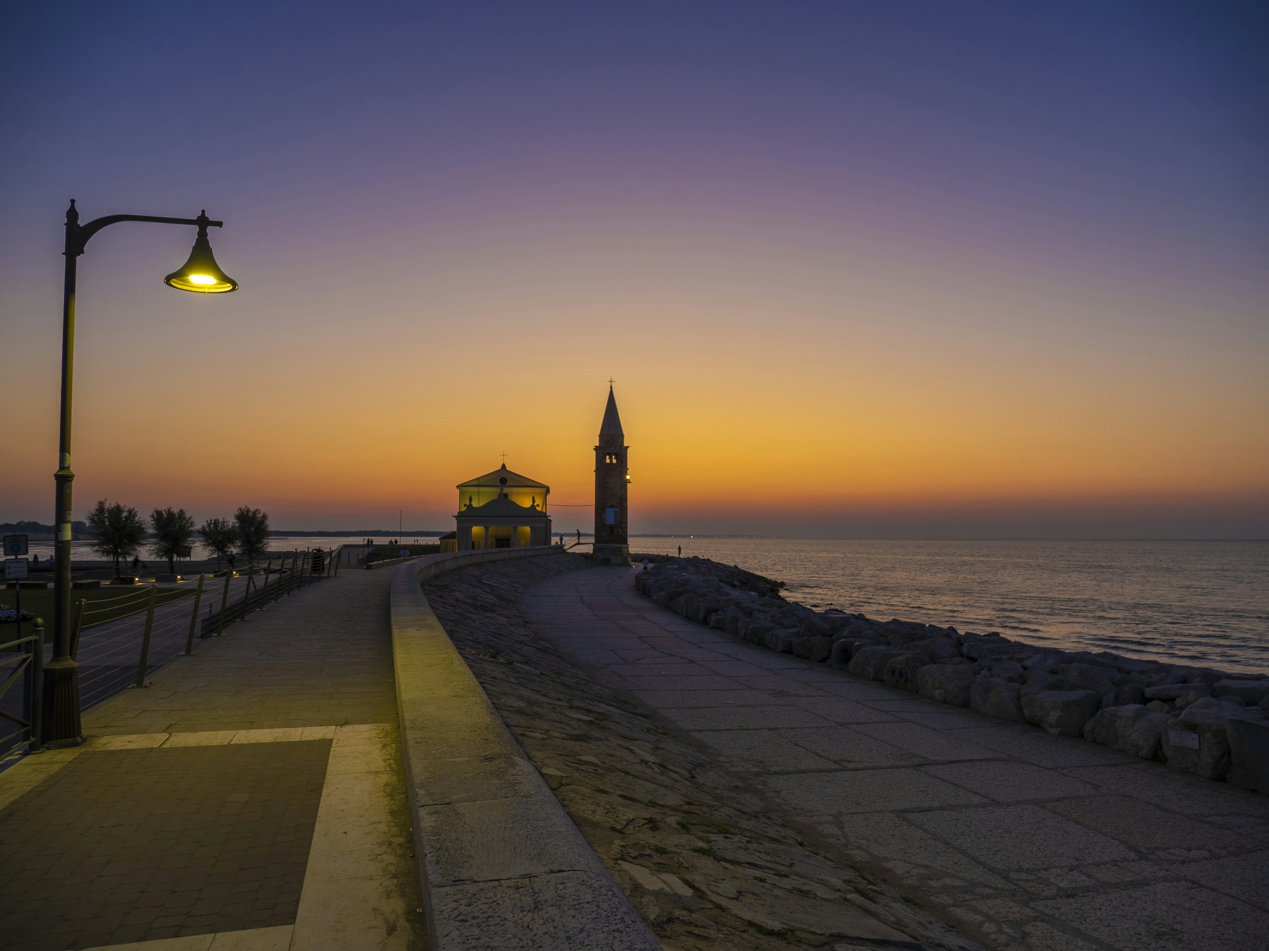 A street light sitting next to a body of water photo – Free Caorle ...