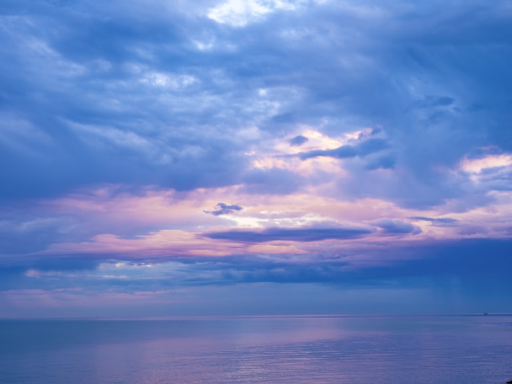 eine Bank, die am Strand unter einem bewölkten Himmel sitzt