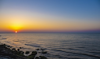 the sun is setting over the ocean on a clear day