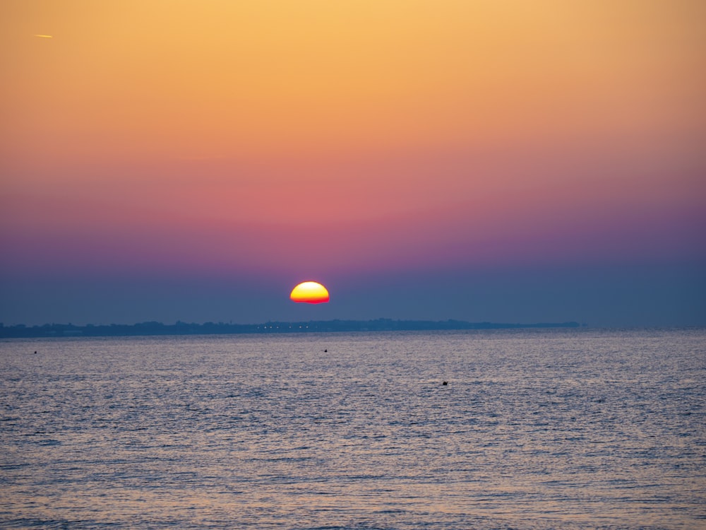 a large body of water with a sunset in the background