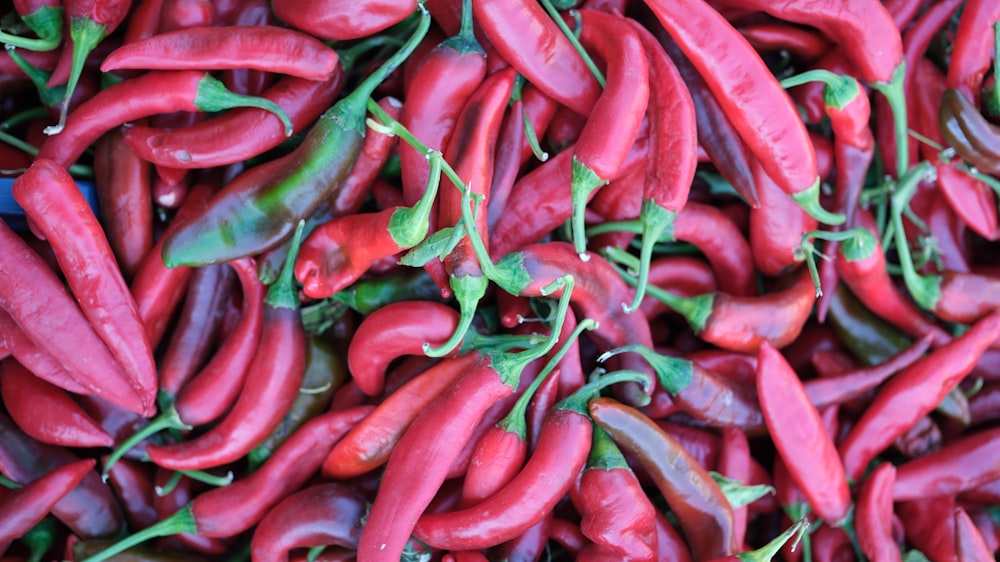 a pile of red peppers with green stems