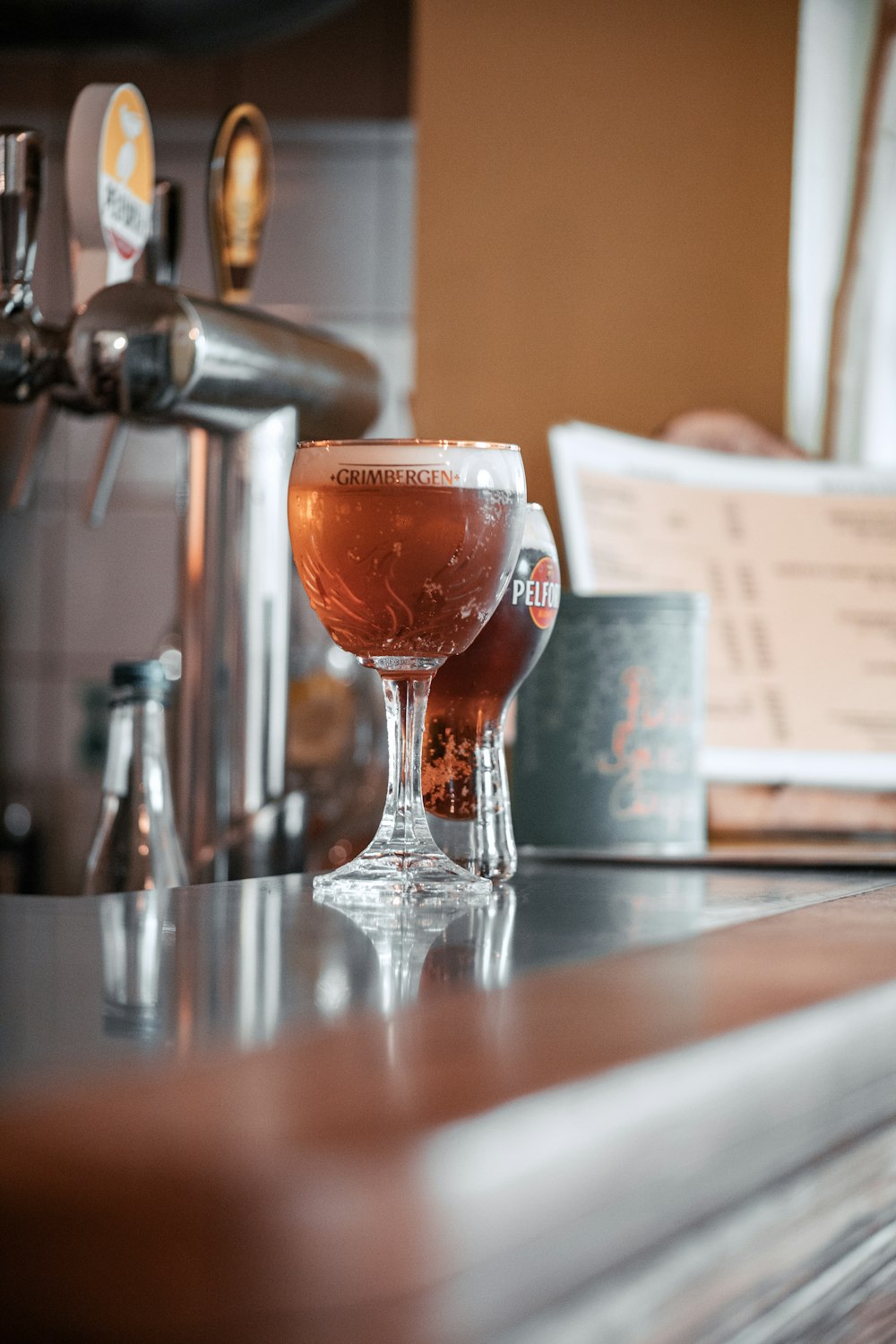 a glass of beer sitting on top of a bar