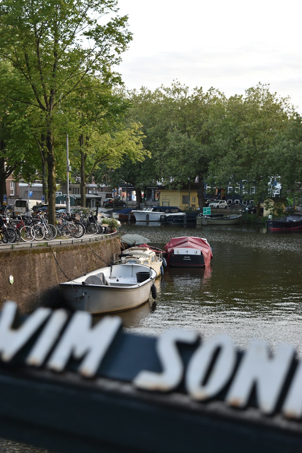 a river filled with lots of boats next to a bridge