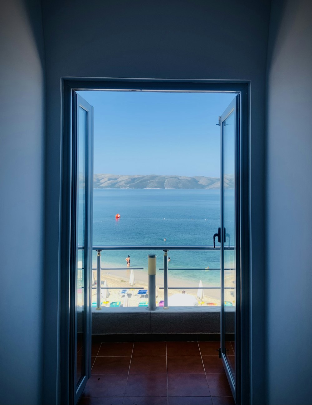 an open door leading to a balcony with a view of the ocean