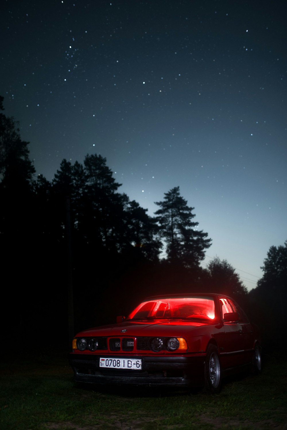 Un'auto rossa parcheggiata nell'erba di notte