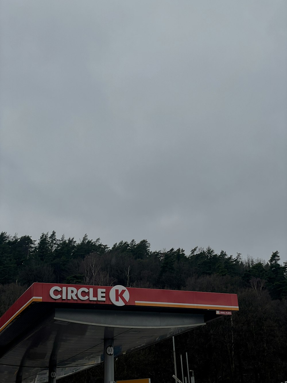 a red and white gas station with trees in the background