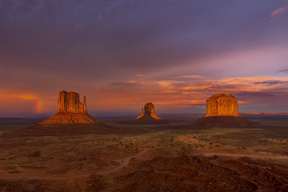 Une vue du coucher de soleil sur le désert avec un arc-en-ciel dans le ciel