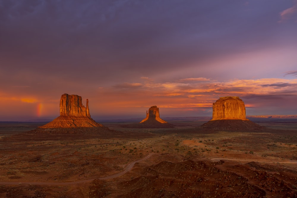 a sunset view of the desert with a rainbow in the sky