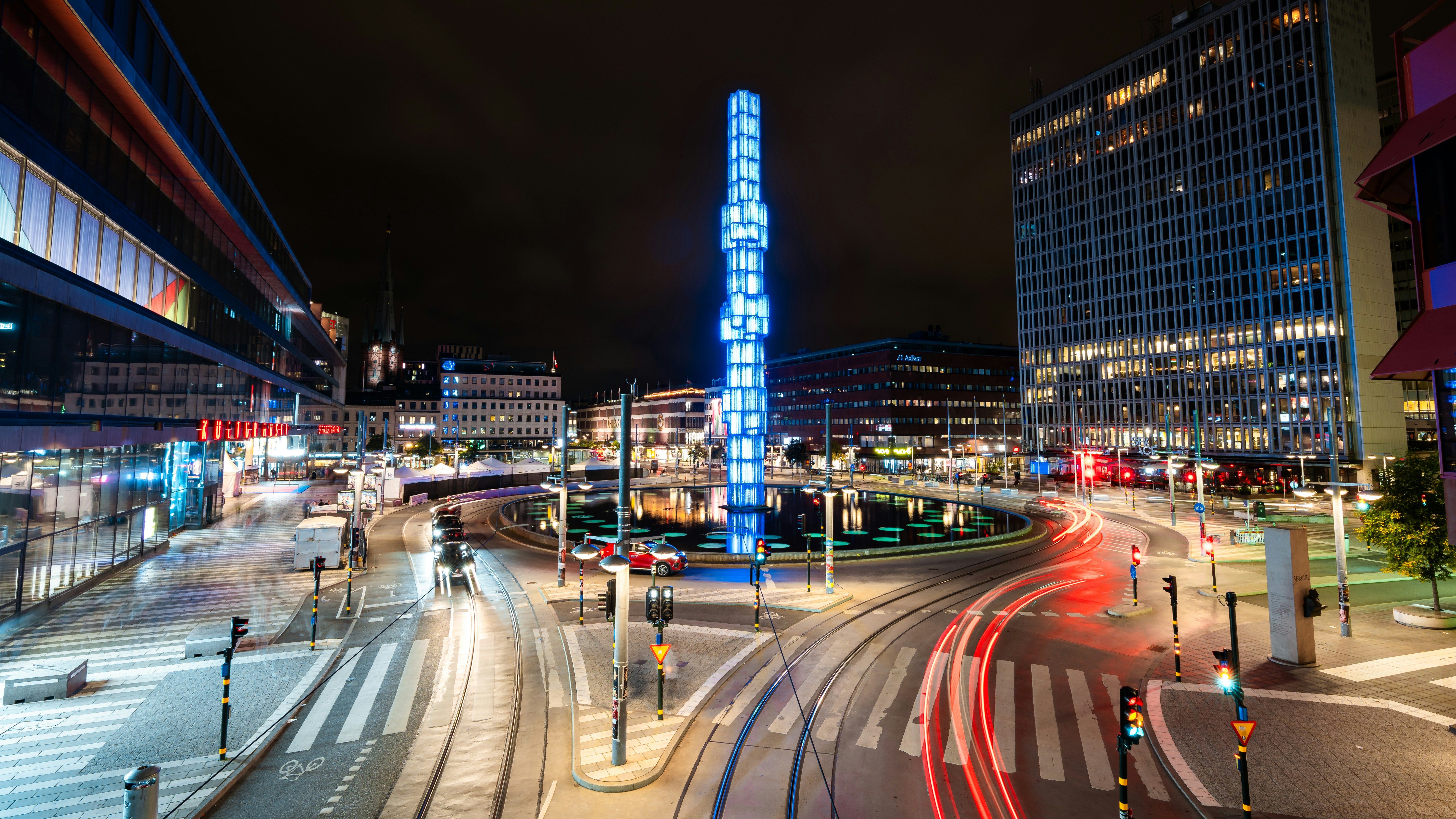 a city street at night with a tall building in the background