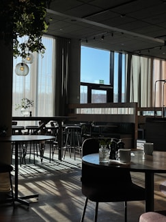 Cozy modern café interior with white and blue tones, sunlight streaming through large windows